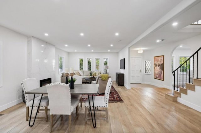 dining area with a premium fireplace, a wealth of natural light, and light wood-type flooring