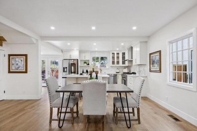 dining space with french doors, a healthy amount of sunlight, and light hardwood / wood-style flooring