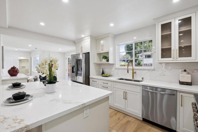 kitchen featuring sink, white cabinetry, stainless steel appliances, light stone countertops, and backsplash