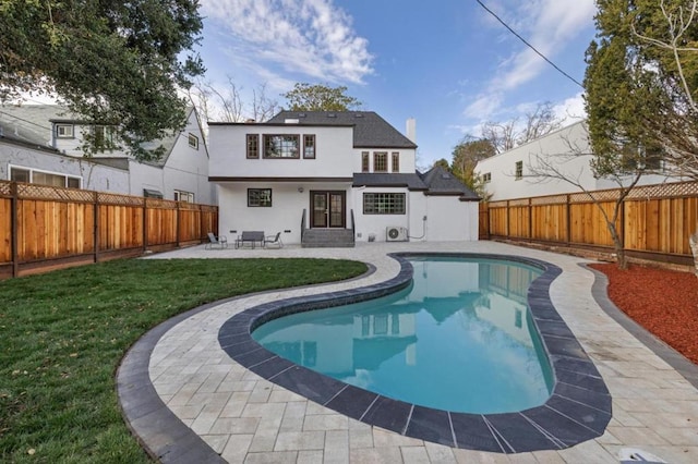 back of property with a fenced in pool, a yard, and a patio area