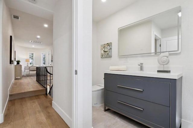 bathroom with wood-type flooring, vanity, and toilet