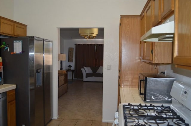 kitchen featuring white gas stove, stainless steel fridge, and light tile patterned floors