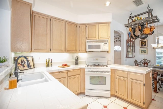 kitchen with sink, white appliances, tile countertops, and light brown cabinets