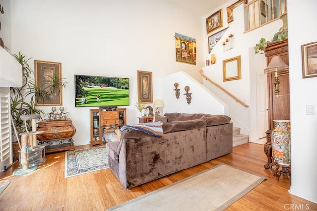 living room with light hardwood / wood-style flooring and a towering ceiling