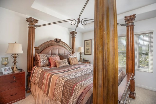 bedroom with a tray ceiling, decorative columns, and light carpet