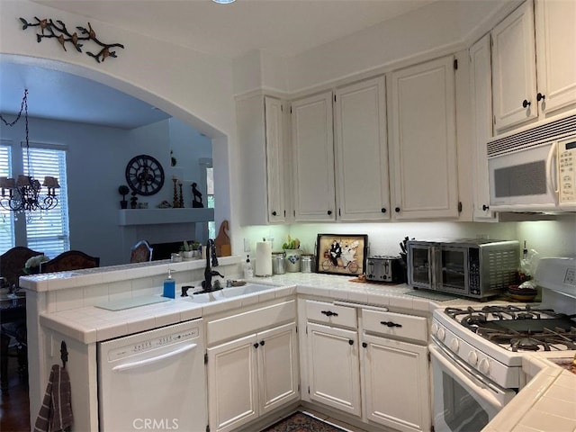 kitchen featuring white appliances, sink, kitchen peninsula, white cabinets, and tile countertops