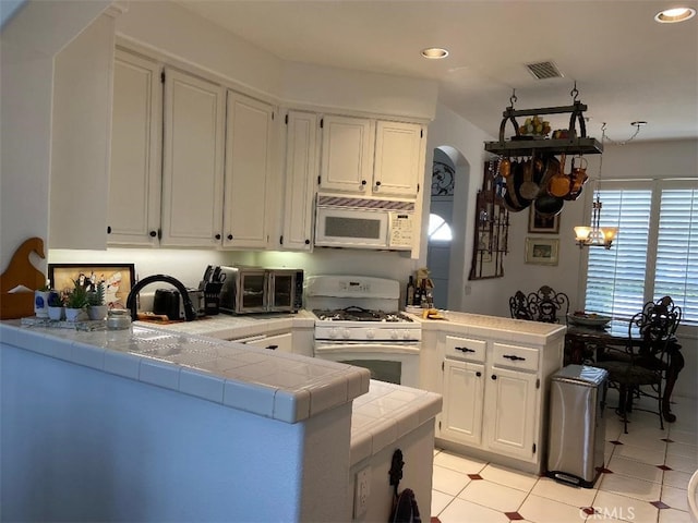 kitchen featuring white appliances, white cabinetry, tile countertops, and kitchen peninsula