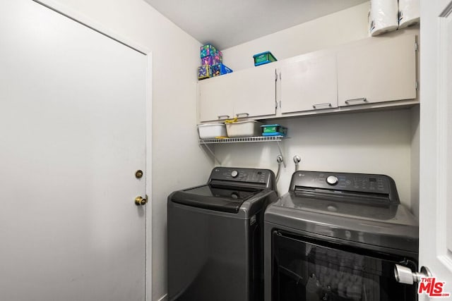 clothes washing area featuring separate washer and dryer and cabinets