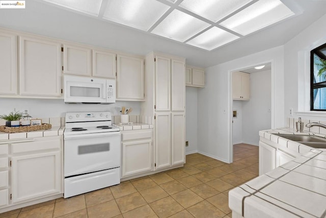 kitchen with sink, white cabinetry, light tile patterned floors, tile counters, and white appliances