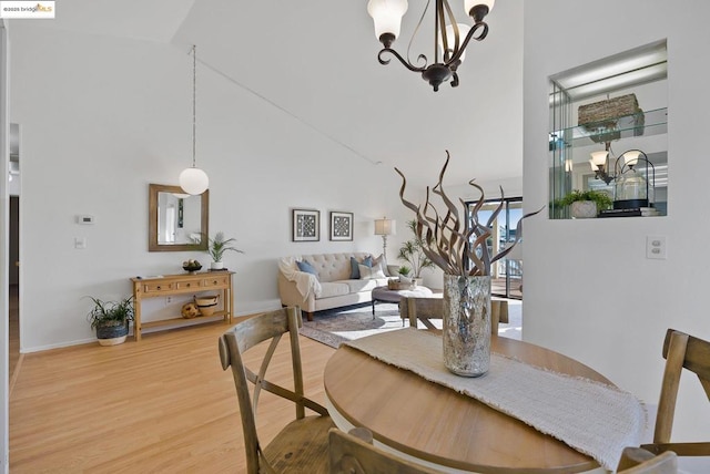 dining area with an inviting chandelier, hardwood / wood-style floors, and a high ceiling