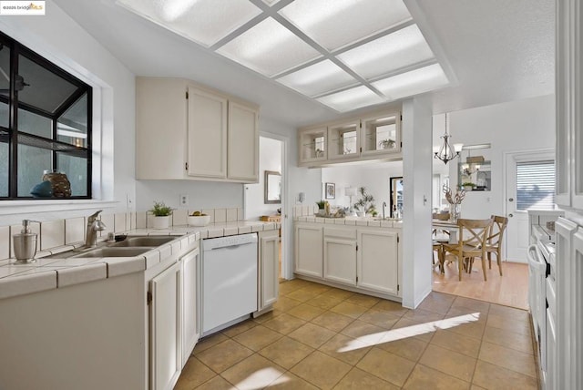 kitchen with tile countertops, white cabinetry, dishwasher, sink, and light tile patterned floors