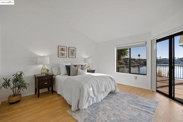 bedroom with a water view, lofted ceiling, light hardwood / wood-style floors, and access to outside