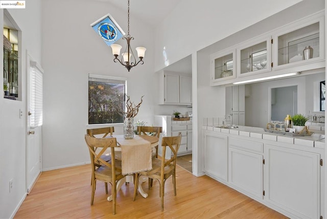 dining area featuring light wood-type flooring, sink, an inviting chandelier, and a towering ceiling