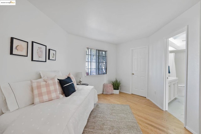 bedroom featuring connected bathroom and light wood-type flooring