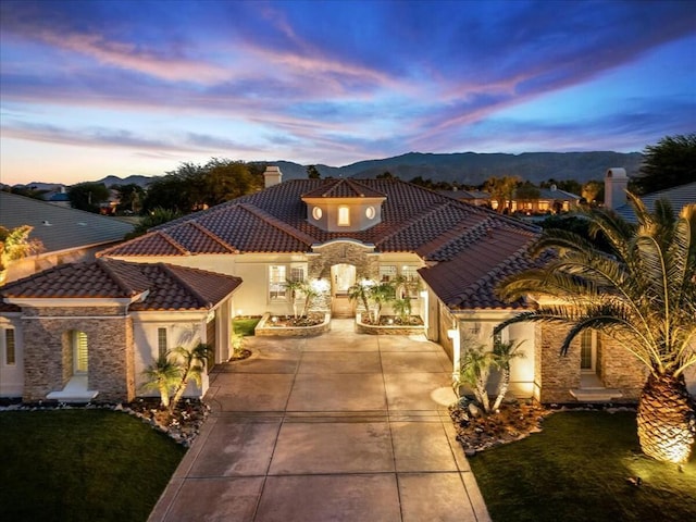 view of front of house with a mountain view and a lawn