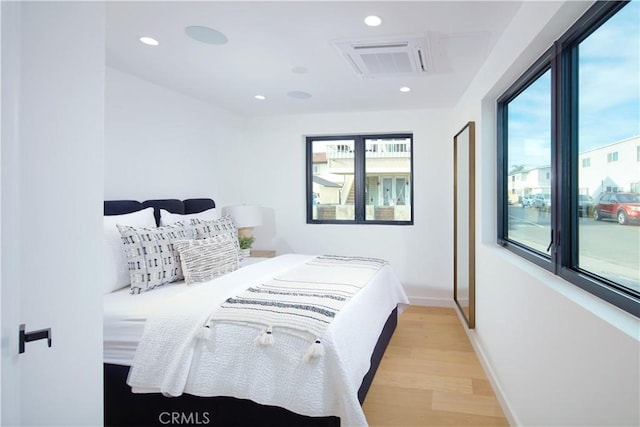 bedroom with multiple windows and light hardwood / wood-style flooring