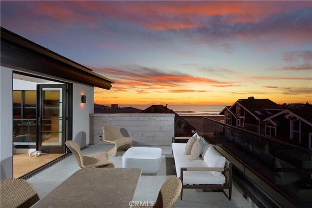 patio terrace at dusk with a balcony and a water view