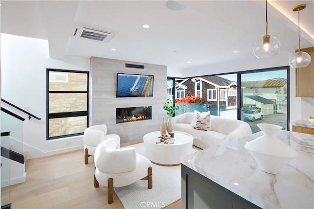 living room featuring a large fireplace and light hardwood / wood-style flooring