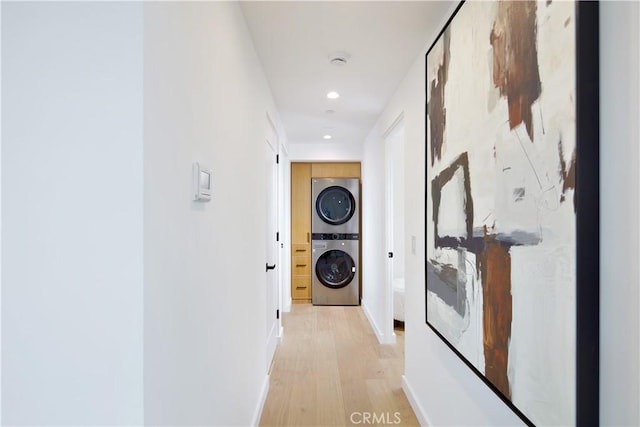 hallway with light hardwood / wood-style floors and stacked washer / drying machine