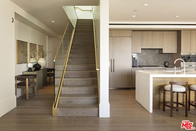 stairway featuring wood-type flooring and sink