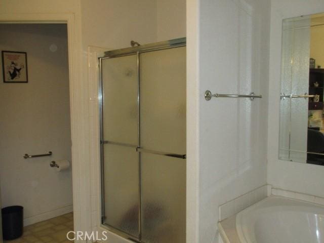 bathroom with an enclosed shower, a garden tub, and baseboards