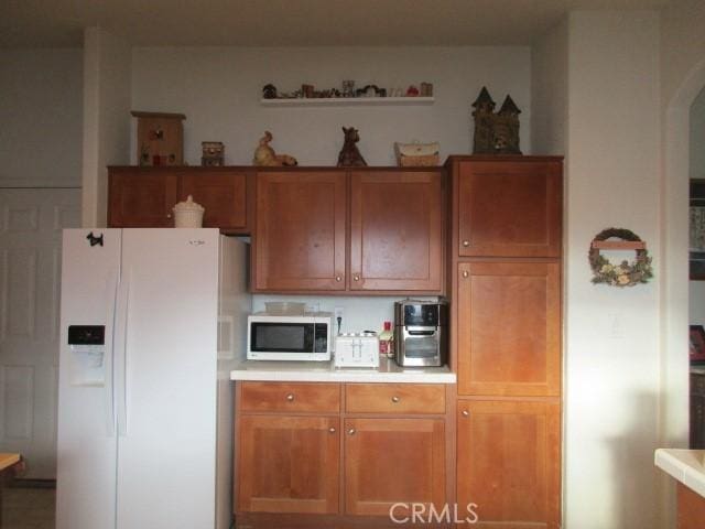 kitchen with brown cabinetry, white appliances, and light countertops