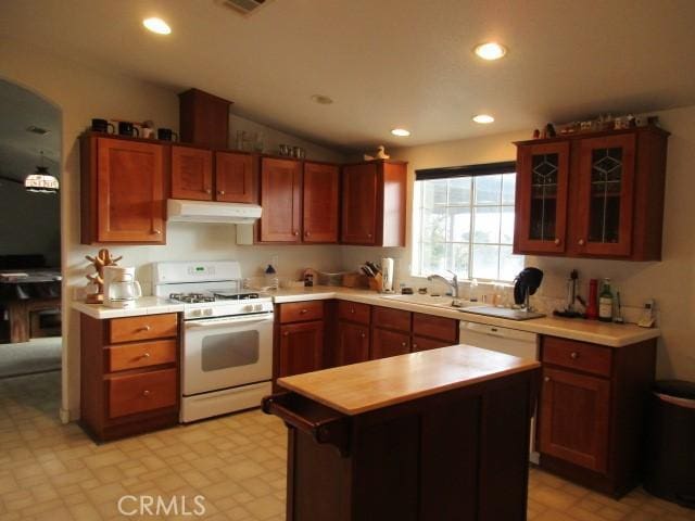 kitchen featuring glass insert cabinets, white appliances, light countertops, and under cabinet range hood