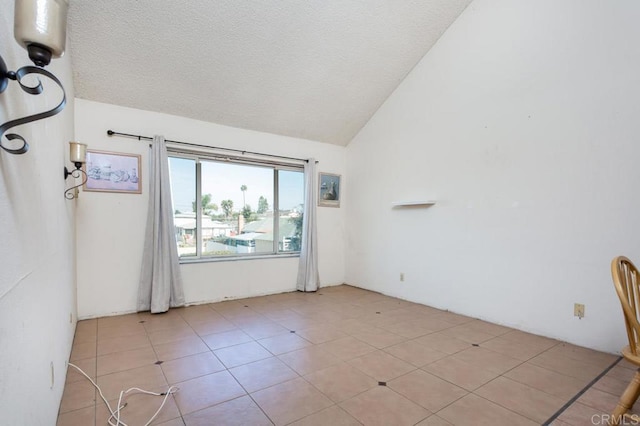 empty room with vaulted ceiling, light tile patterned floors, and a textured ceiling