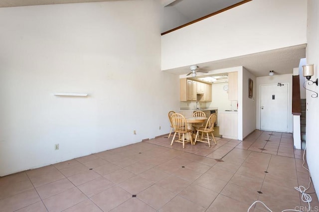 unfurnished dining area with ceiling fan, high vaulted ceiling, and light tile patterned floors