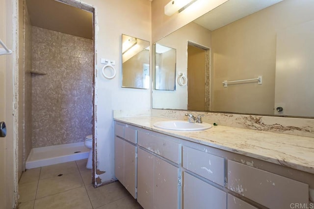 bathroom with tiled shower, tile patterned floors, toilet, and vanity