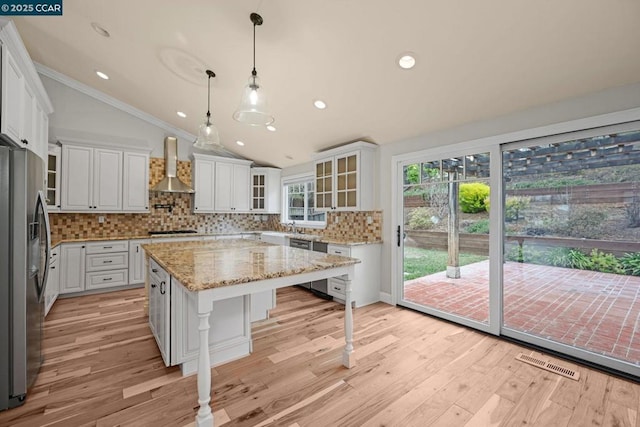 kitchen with wall chimney range hood, a center island, stainless steel refrigerator with ice dispenser, white cabinets, and black gas stovetop