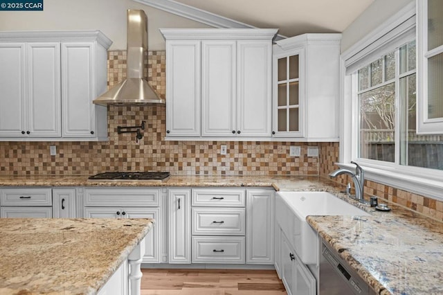 kitchen featuring white cabinetry, wall chimney exhaust hood, stainless steel appliances, and decorative backsplash