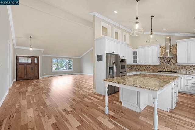 kitchen with wall chimney range hood, white cabinets, and a spacious island