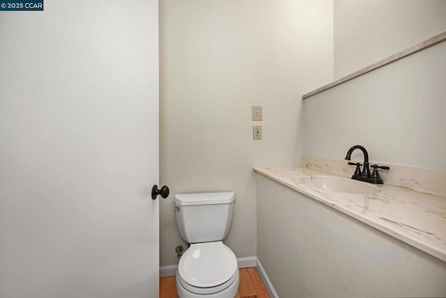 bathroom with wood-type flooring, vanity, and toilet