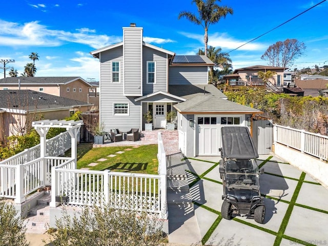 back of house featuring a patio, a lawn, and solar panels