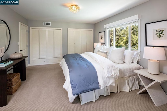 bedroom with light carpet and two closets