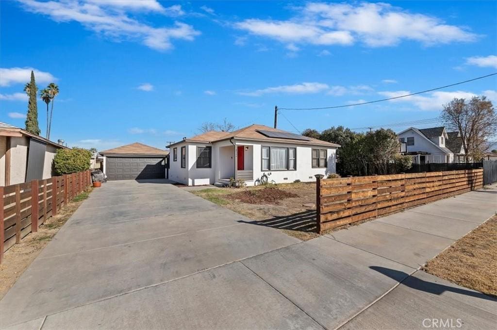 single story home featuring an outbuilding, a garage, and solar panels