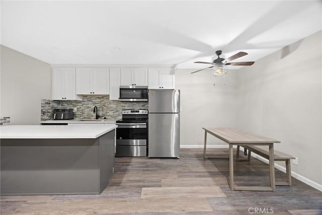 kitchen with white cabinets, backsplash, hardwood / wood-style flooring, ceiling fan, and stainless steel appliances