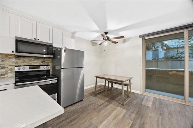 kitchen featuring appliances with stainless steel finishes, white cabinets, decorative backsplash, ceiling fan, and light hardwood / wood-style flooring