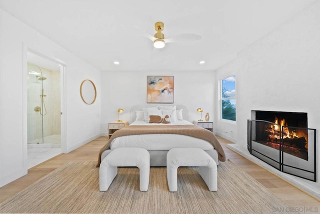 bedroom featuring connected bathroom, light hardwood / wood-style flooring, and ceiling fan