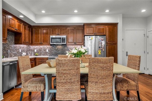 kitchen featuring stainless steel appliances, hardwood / wood-style floors, a center island, and a breakfast bar area