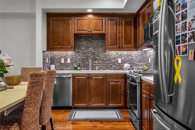 kitchen featuring stainless steel appliances, hardwood / wood-style flooring, sink, and decorative backsplash