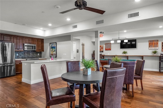 dining room with dark hardwood / wood-style flooring, ceiling fan, and bar