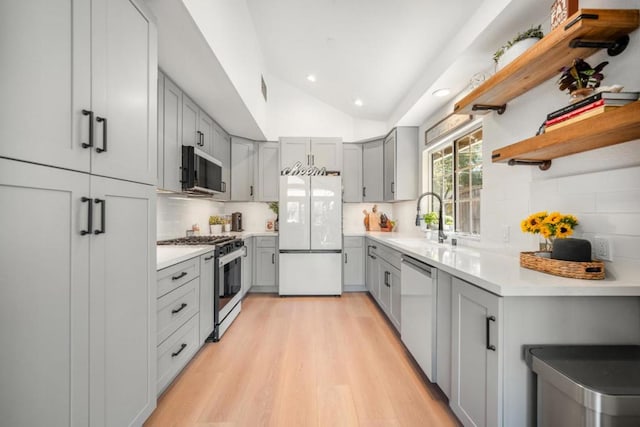 kitchen featuring sink, dishwasher, gray cabinetry, stainless steel gas range oven, and white fridge