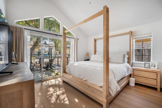 bedroom with hardwood / wood-style flooring, high vaulted ceiling, and access to outside