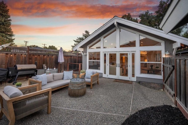 patio terrace at dusk featuring a grill, an outdoor hangout area, and french doors