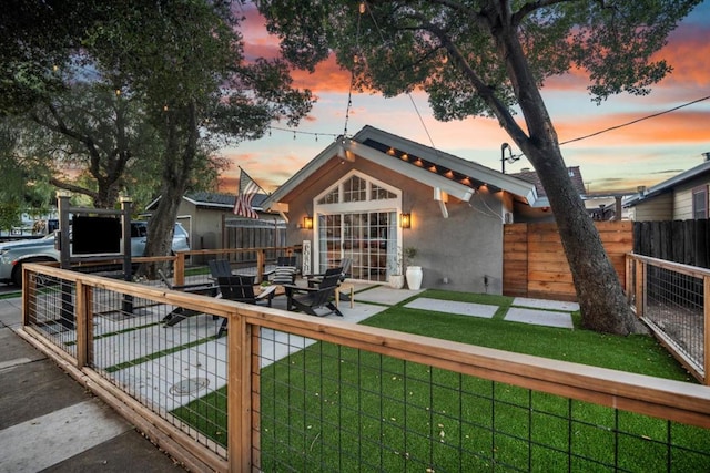 back house at dusk featuring a lawn