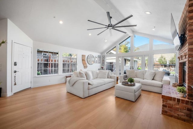 living room with high vaulted ceiling, a brick fireplace, light hardwood / wood-style flooring, beamed ceiling, and ceiling fan