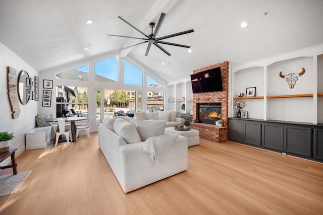 living room featuring high vaulted ceiling, light hardwood / wood-style flooring, beamed ceiling, ceiling fan, and a fireplace