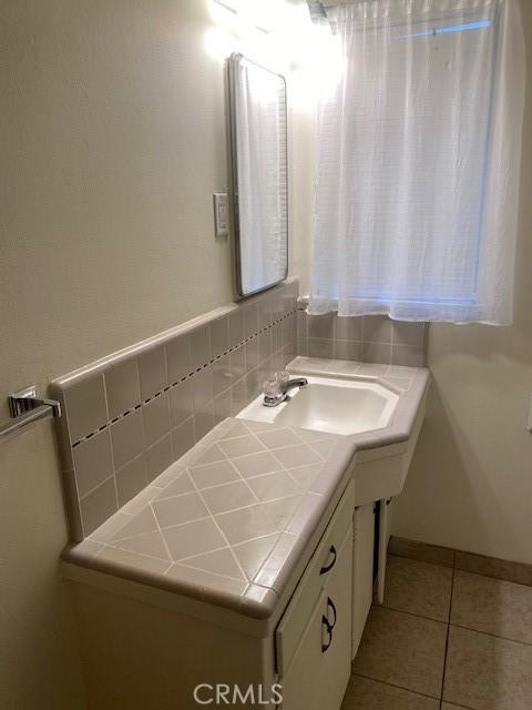 bathroom with vanity, tile patterned flooring, and decorative backsplash